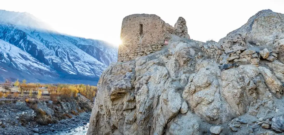 A solitary fortress tower on a ridge above the turquoise Panj river
